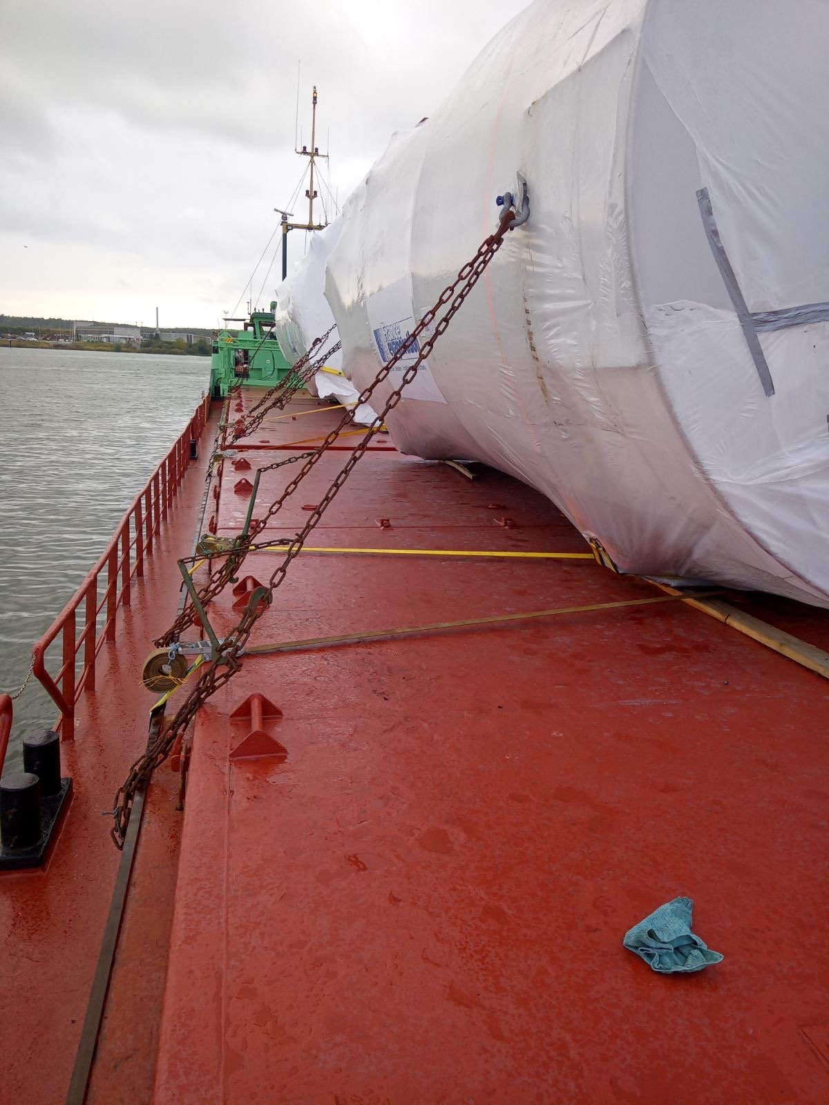 Two wrapped storage tanks secured with chains and web lashings on the vessel deck