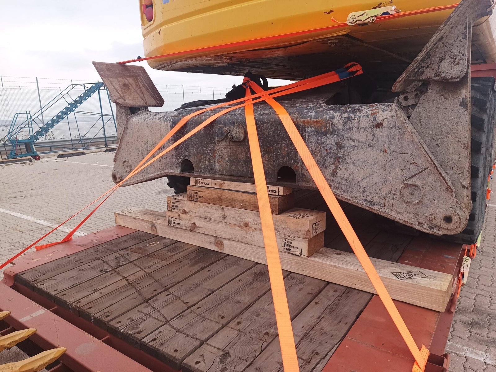 Excavator bucket supported on timber blocks and secured with straps on the flat-rack at London Gateway